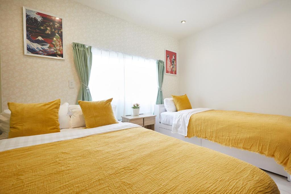 a bedroom with two beds with yellow sheets and a window at Cozy Room in東京浅草二階建の一軒家 in Tokyo