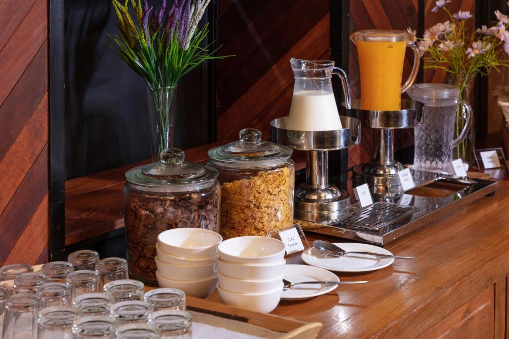 A self-service breakfast station with cereal, drinks, bowls and glasses.