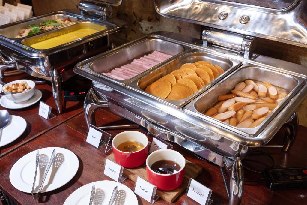 A heated breakfast buffet with pastries, sausages and covered hot dishes.