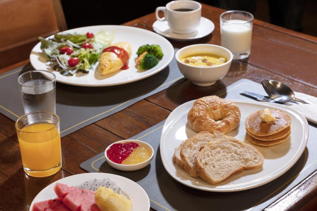 A prepared breakfast spread with pastries, fruit, salad, juice, coffee and yoghurt.