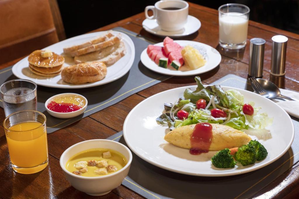 A plated breakfast combines an omelette, salad, fruit, pastries and drinks.