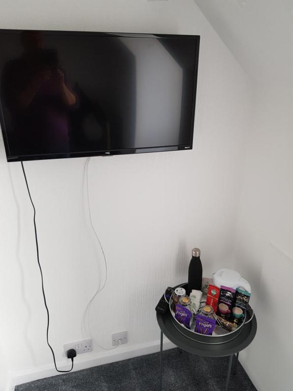 uma televisão de ecrã plano pendurada numa parede com uma mesa em The Cedars Hotel em Lincolnshire
