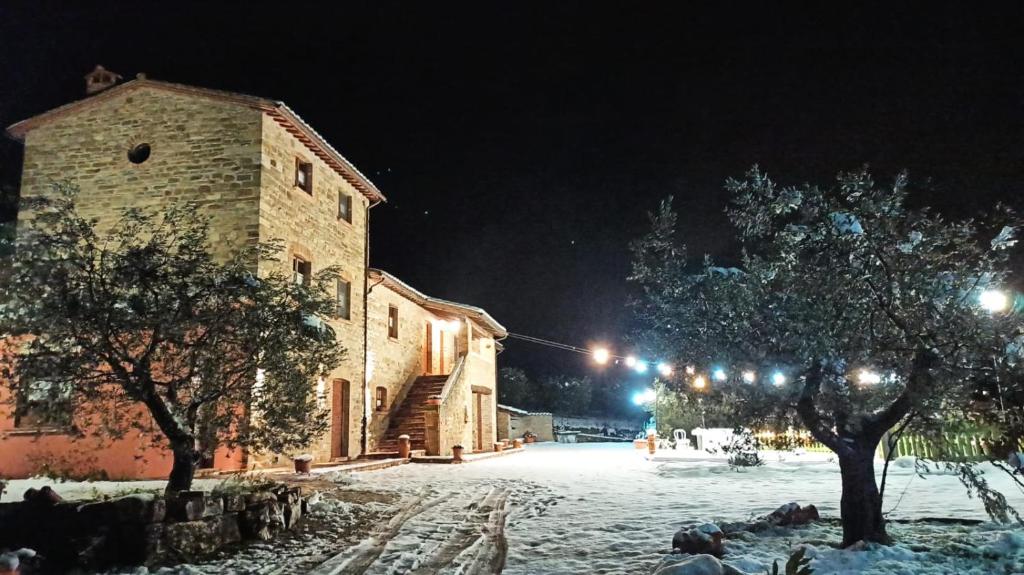 une rue enneigée la nuit avec un bâtiment dans l'établissement Il Casalino, à Gualdo Tadino