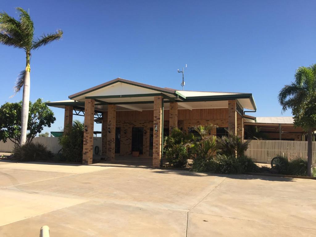 a building with a palm tree in front of it at Boulder Opal Motor Inn in Winton