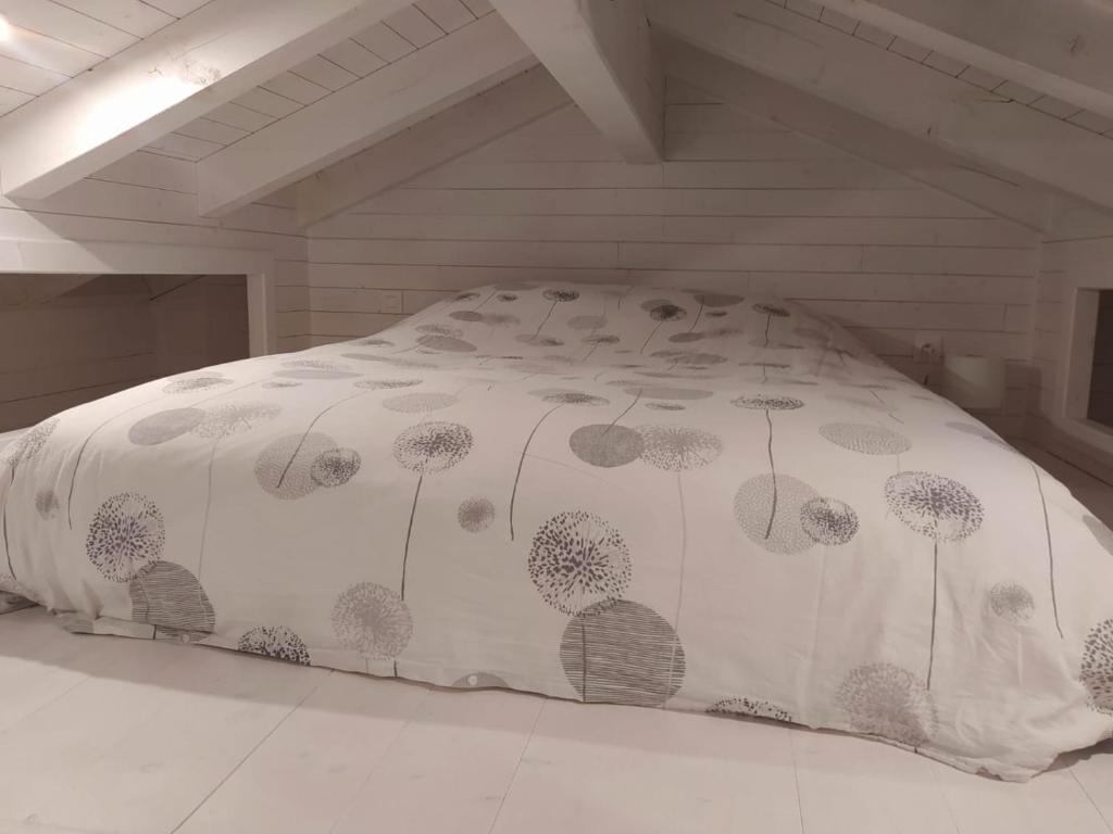 een bed met een witte sprei met paardenbloemen erop bij Maisonnette in Talloires