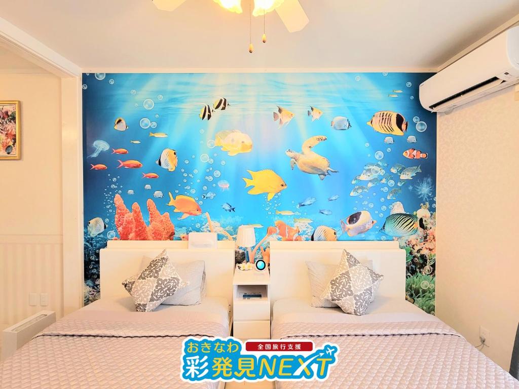 - une chambre avec 2 lits et une fresque murale représentant des poissons dans l'établissement Villa Blu Okinawa Chatan 3-3 ヴィラブルー沖縄北谷3-3 "沖縄アリーナ徒歩圏内の民泊ホテル", à Chatan