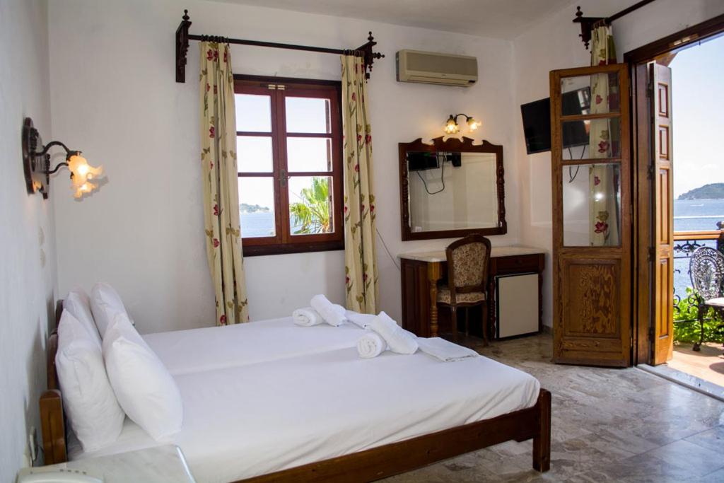 a bedroom with a bed and a mirror and a window at Hotel Villa Orsa in Skiathos Town