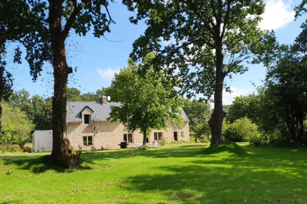 een oud stenen huis met bomen op de voorgrond bij Maison de famille près de la mer in Bénodet