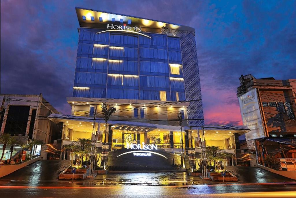 a hotel building with a sign on it at night at Horison Tasikmalaya in Tasikmalaya