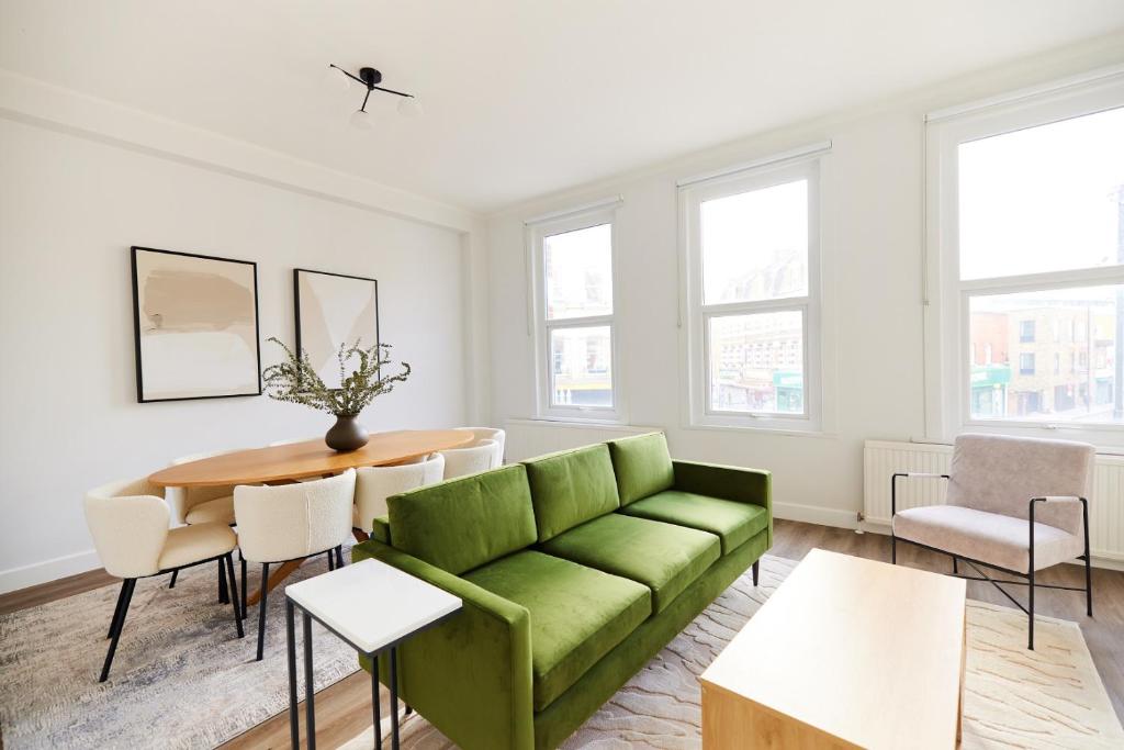 een woonkamer met een groene bank en een tafel bij The Fulham Escape - Alluring 5BDR Flat in Londen