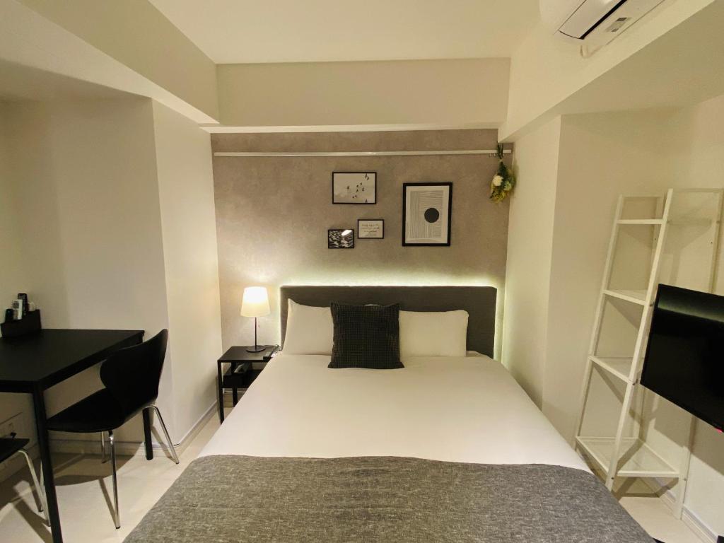 um quarto com uma cama e uma secretária e uma cama sidx sidx em FLOWER TERRACE Higashi Shinjuku em Tóquio