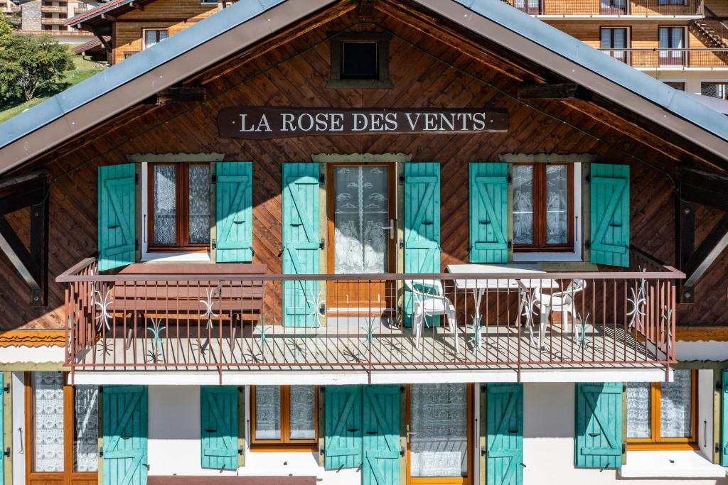 Cette maison en rondins dispose d'un balcon et de volets bleus. dans l'établissement La Rose des Vents N 3, à Châtel