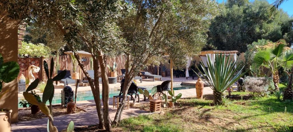 um jardim com piscina e algumas árvores e arbustos em Les Trois Paons em Taroudant