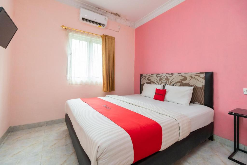 a bedroom with a large bed with pink walls at RedDoorz Syariah near Transmart Padang in Padang