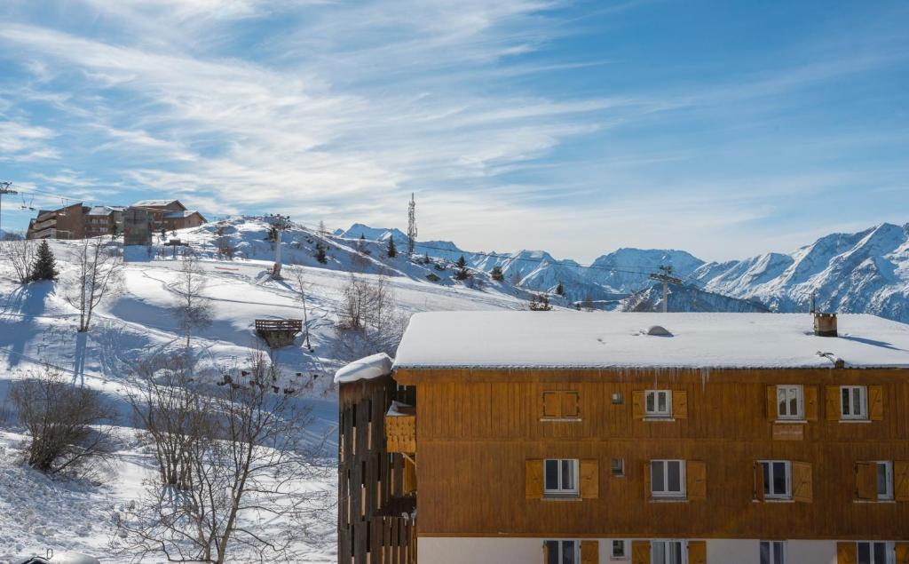 a building in the snow with mountains in the background at Hotel Le Chamois in L&#39;Alpe-d&#39;Huez