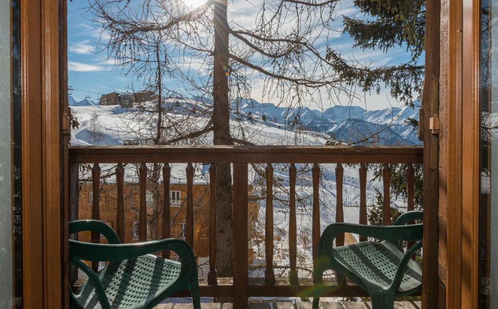 a balcony with two chairs and a view of the mountains at Hotel Le Chamois in L&#39;Alpe-d&#39;Huez