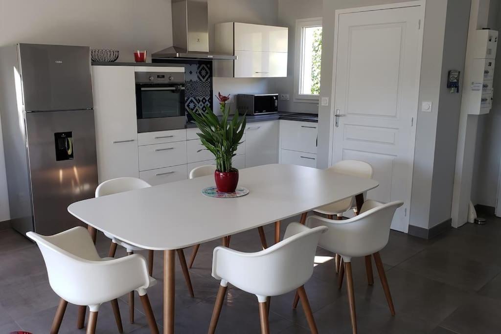 cocina blanca con mesa blanca y sillas blancas en Maison au calme et proximité plage. en Saint-Quay-Portrieux