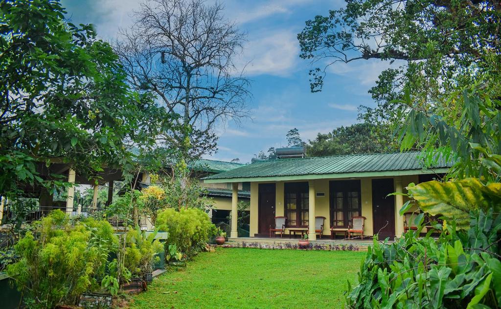 una casa con techo verde y patio en Blue Magpie Lodge Sinharaja, en Kudawe