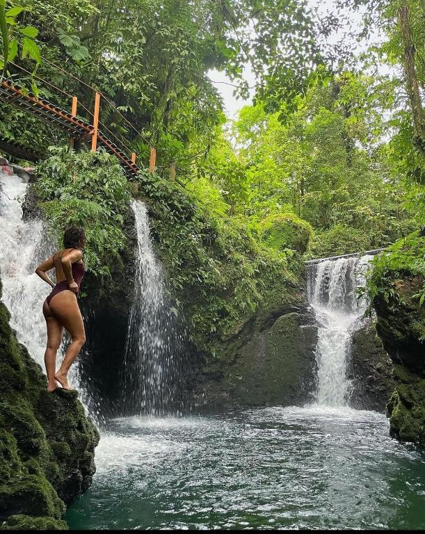 a woman in a bikini standing in front of a waterfall at Pozas y Cascadas La Presa in Río Cuarto