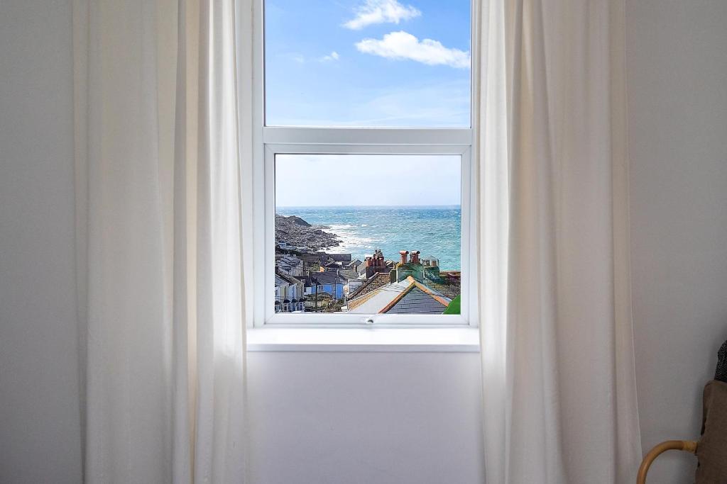 Bright & beautiful 4 bedroom house with sea views في بورتلاند: نافذة مفتوحة مطلة على المحيط
