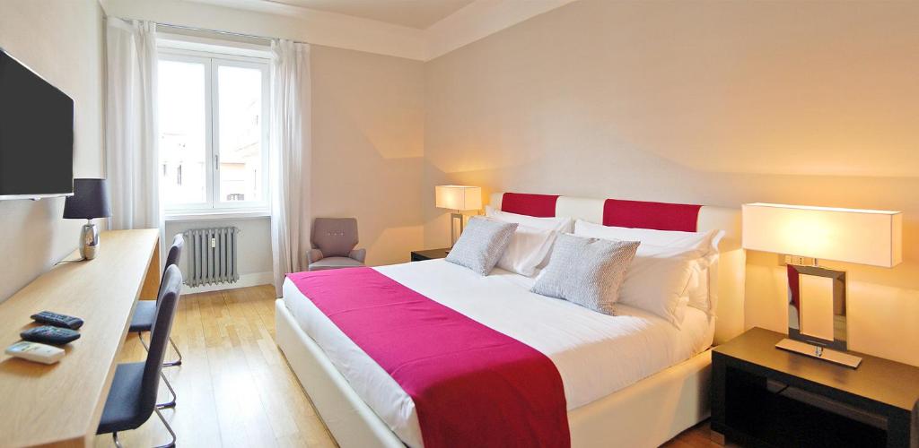 a hotel room with a large bed and a desk at Adamas Luxury Suite in Rome