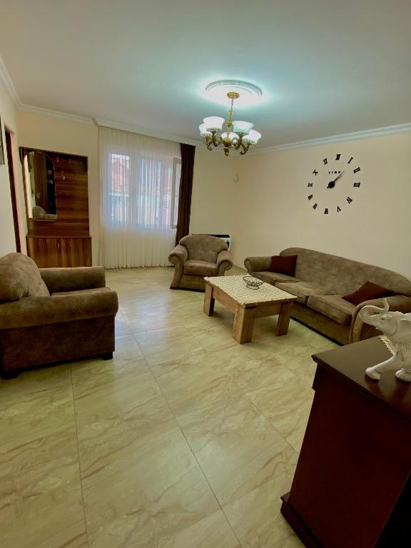 uma sala de estar com sofás e um relógio na parede em Family Home em Batumi
