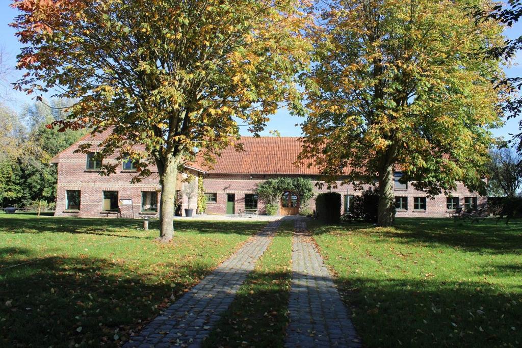 uma casa com duas árvores em frente em De Bogaerd em Lo-Reninge