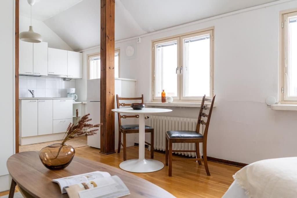 een keuken en een woonkamer met een tafel en stoelen bij Upper floor studio with a sea view in Helsinki