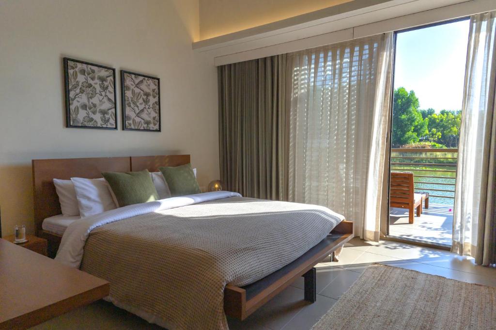 a bedroom with a large bed and a large window at Life At REPOSE- Lake Villas Resort & Club in Chor Warodra