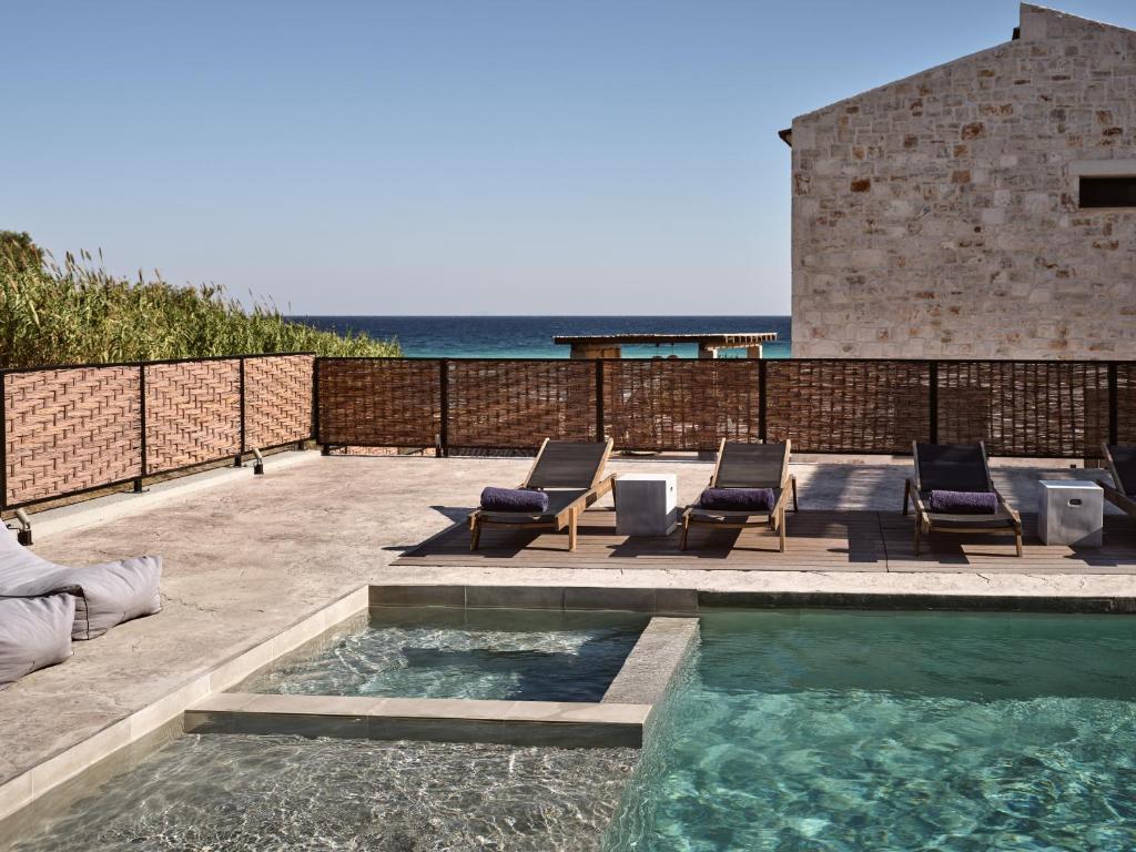 a swimming pool with lounge chairs and the ocean at Seaside Luxury LaTerre, Zante Zen By ThinkVilla in Psarou