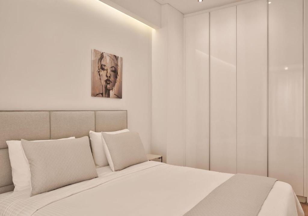 sypialnia z białym łóżkiem i obrazem na ścianie w obiekcie Cute n Comfort Luxury Condo in Kolonaki w Atenach