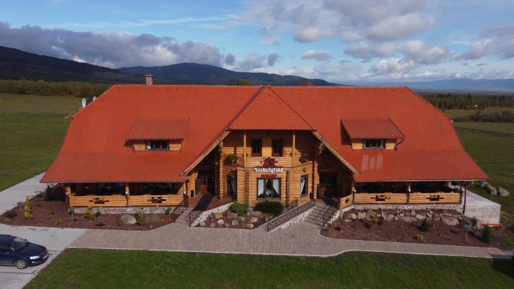 Székelyföld Fogadó في Borzont: اطلالة جوية على منزل بسقف احمر