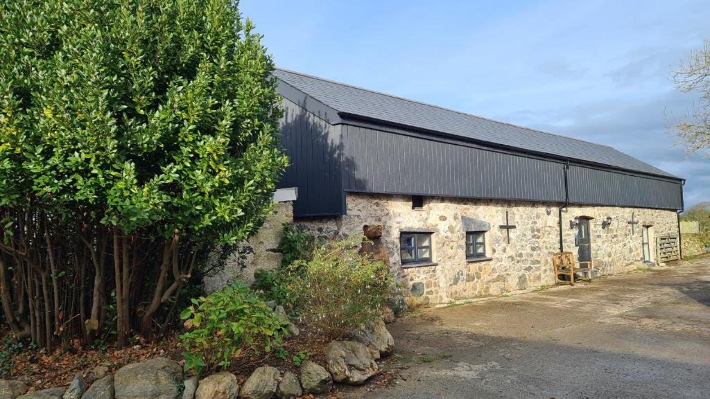 德维兰Peibio at Llanfair Hall的树旁有一栋黑色屋顶的石头房子。