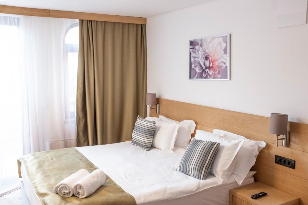 een slaapkamer met een bed met witte lakens en kussens bij Prenoćište restoran Bukulja in Arandjelovac