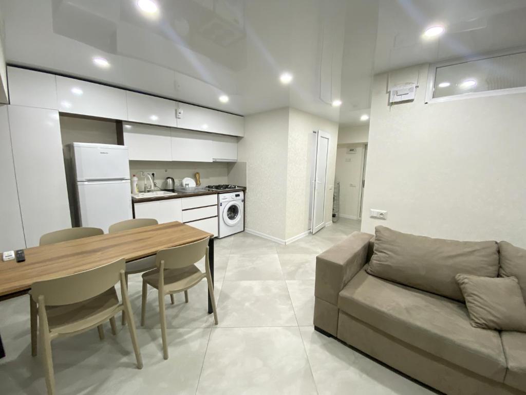 GSS - B Apartment في تبليسي: مطبخ وغرفة معيشة مع طاولة وأريكة