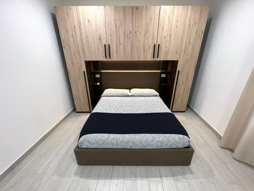 a bedroom with a bed with a wooden headboard at AIR σϝ HOME Aραɾƚɱҽɳƚ ᴍᴀʀᴇɴᴄᴏ in Novi Ligure