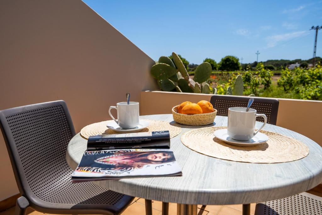 - une table avec deux tasses de café et une corbeille de fruits dans l'établissement Apartamentos Marcelino - Formentera Break, à Es Pujols