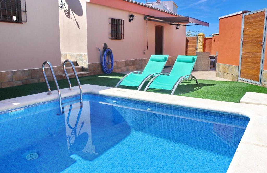 Chalet Sultan con piscina في كونيل دي لا فرونتيرا: مسبح والكراسي الزرقاء بجانب المنزل