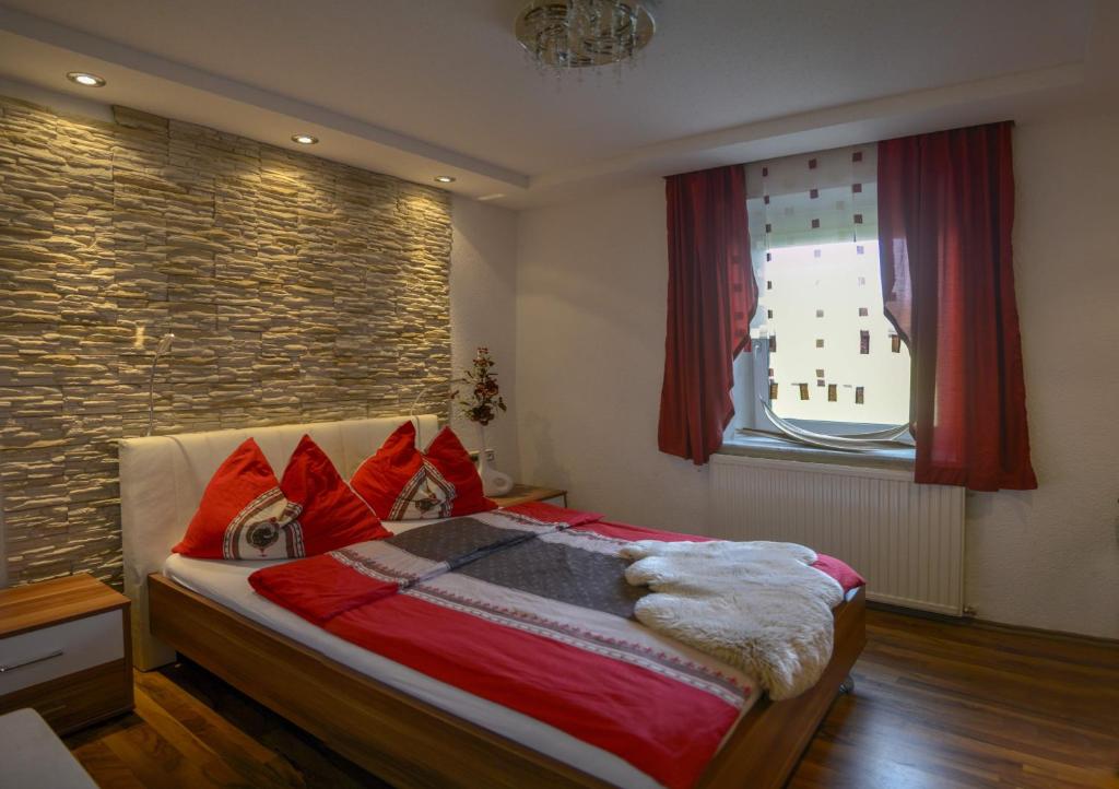 a bedroom with a bed with red pillows and a brick wall at Beates Daham in Fohnsdorf