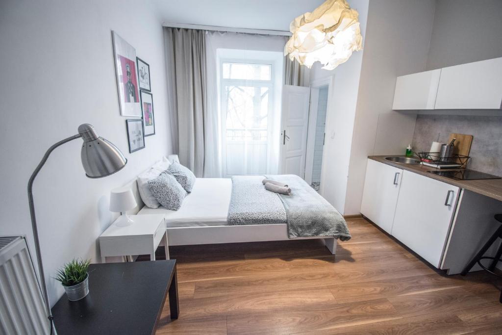 a white bedroom with a bed and a kitchen at SL apartments in Krakow