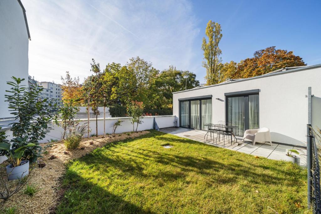 podwórko białego domu z trawnikiem w obiekcie Arbio I Liv's Place Lux Apartments w Wiedniu