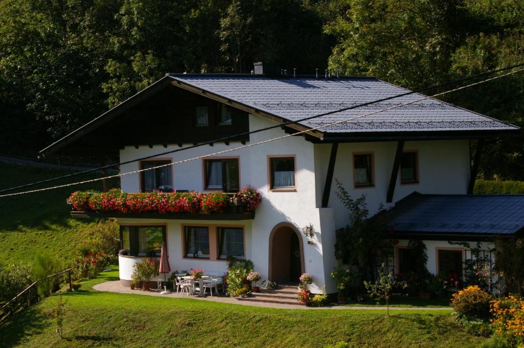 a white house with a black roof with flowers at Haus Brigitte Rettensteiner in Schladming