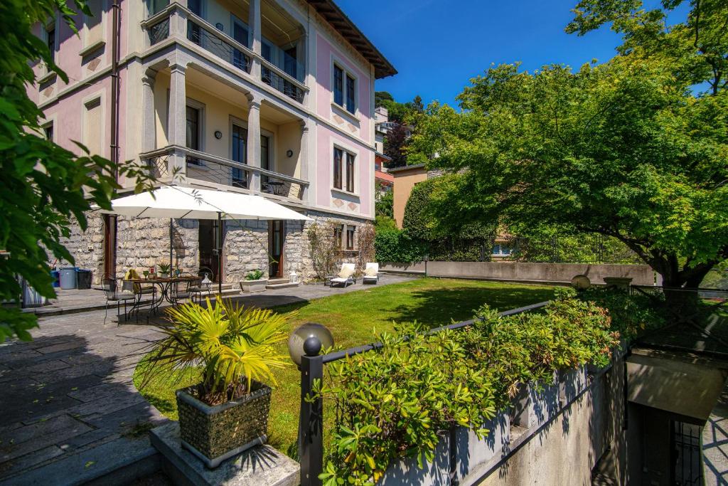 a building with an umbrella in front of a yard at Charming & Luxury Villa Como Lake in Como