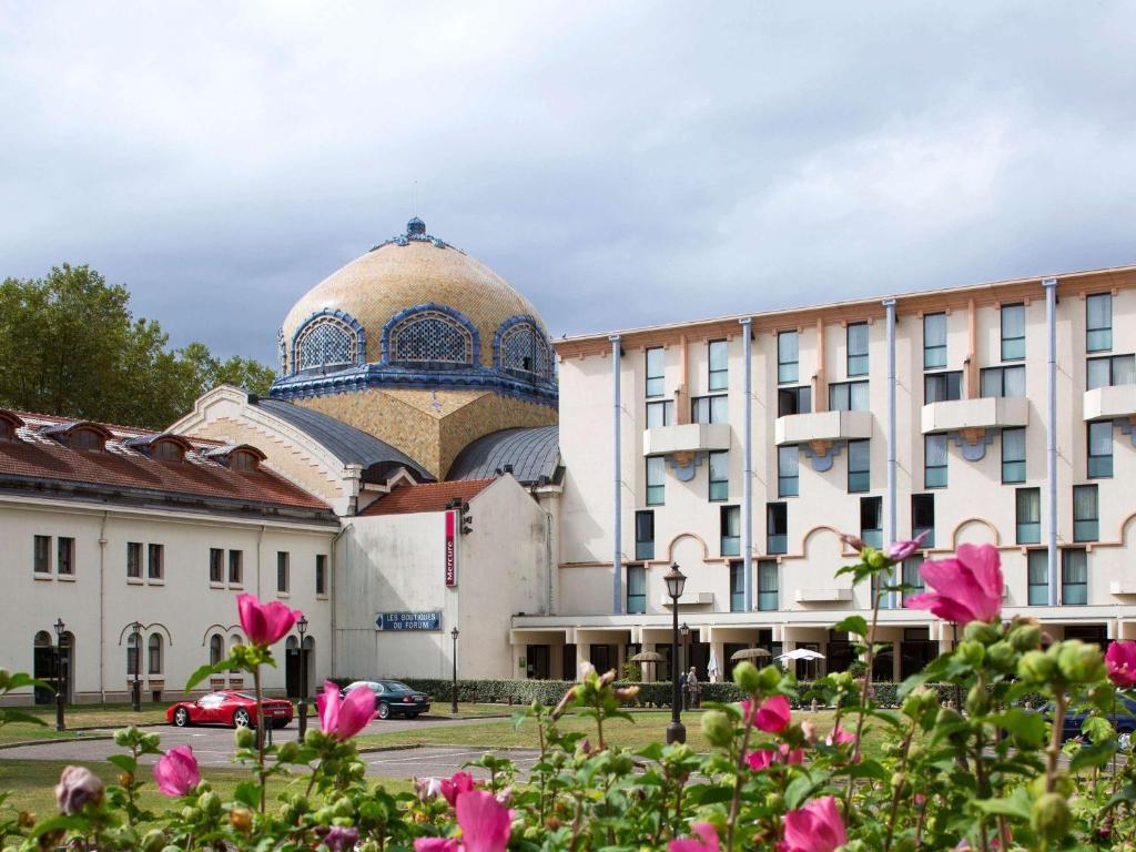 a building with a mosque in the background with pink flowers at Mercure Vichy Thermalia in Vichy