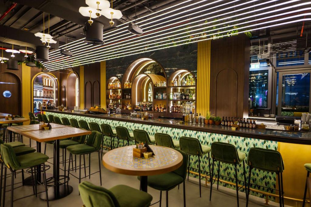 a bar with green chairs and tables in a restaurant at Radisson Beach Resort Palm Jumeirah in Dubai