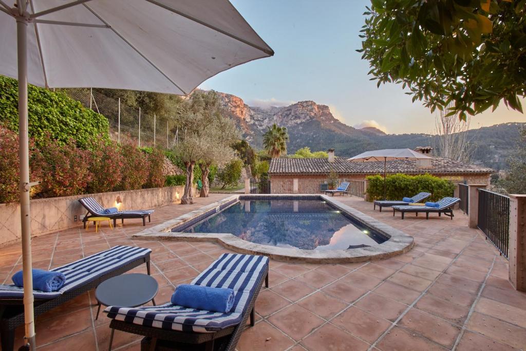 uma piscina com cadeiras e um guarda-sol em Villa Carmin - Deia em Deia