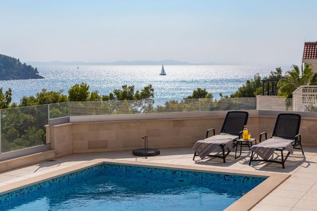 a swimming pool with two chairs and a table on a patio at SEAFRONT VILLA for 10 people! in Milna
