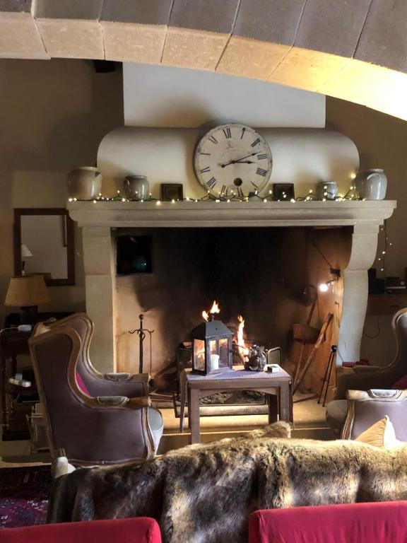 a living room with a fireplace with a clock at L'ORANGERIE Chambres d'hotes de charme in Valros