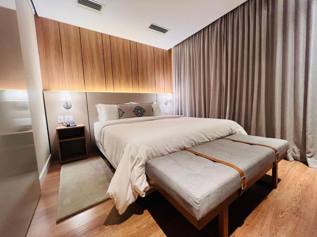 - une chambre avec un lit et un banc dans l'établissement MRG- Exclusive Gramado Loft 1D - 10 minutos do Centro, à Gramado