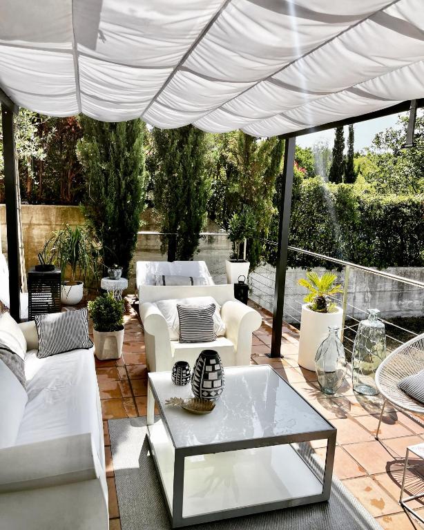 a patio with white furniture under a white umbrella at Estilosa casa golf suites in Gorraiz